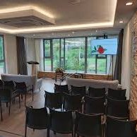 Een huiselijke afscheidsruimte met stoelen en een scherm met een presentatie.