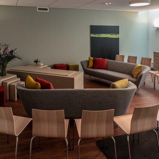 Moderne zithoek met banken, stoelen en een houten tafel, versierd met kussens.